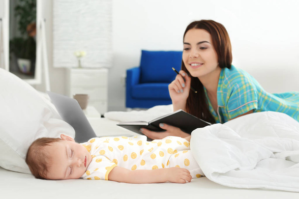 Baby sleeping near mother while she working at home - Photo, image