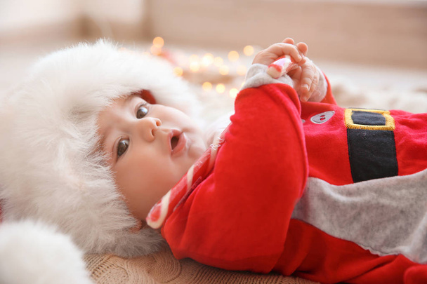 Happy cute baby in Santa suit with candy lying on knitted fabric - Foto, imagen
