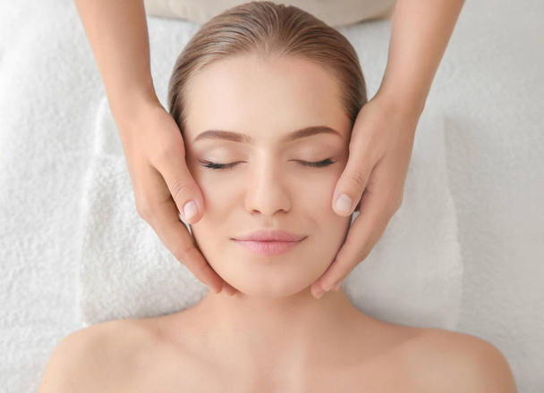 Young woman enjoying of facial massage in spa salon - Foto, Imagem