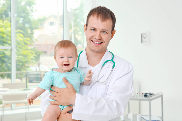 Male pediatrician holding beautiful baby girl indoors - Zdjęcie, obraz