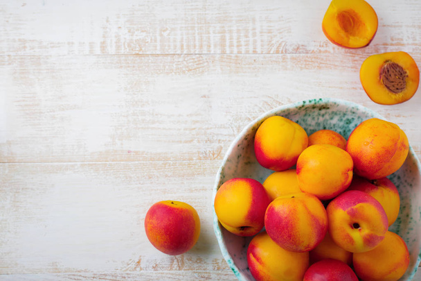 Fresh juicy fruit nectarines in metal grid on  white wooden background. - Foto, immagini