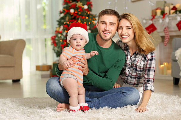Happy parents with baby in decorated room for Christmas - Фото, изображение