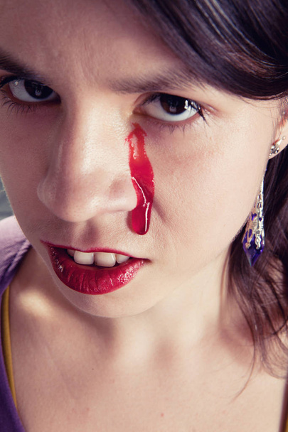 girl in purple straitjacket with bloody tears - Fotó, kép