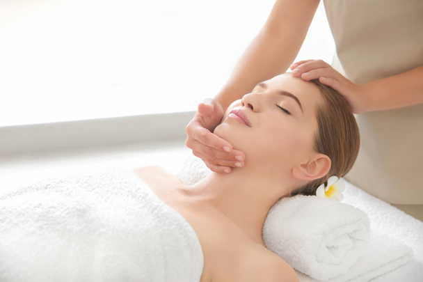 Young woman enjoying of facial massage in spa salon - Fotó, kép