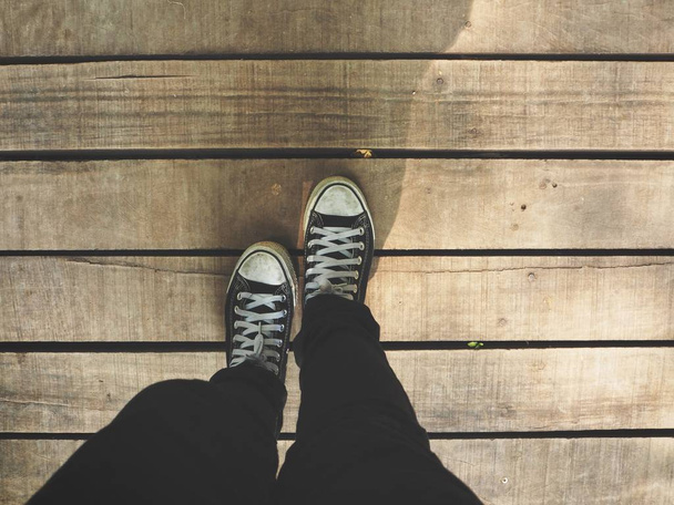 обрізаний знімок ніг в кросівках на дерев'яній підлозі
 - Фото, зображення