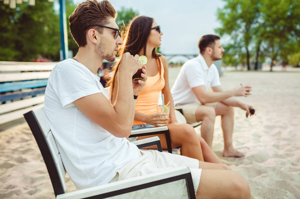 Young people enjoying summer vacation sunbathing drinking at beach bar - Fotó, kép