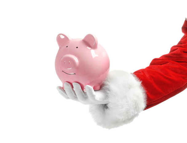 Santa Claus holding piggy bank on white background - Foto, afbeelding