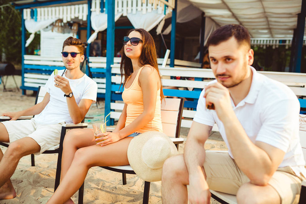 Young people enjoying summer vacation sunbathing drinking at beach bar - Foto, Imagen