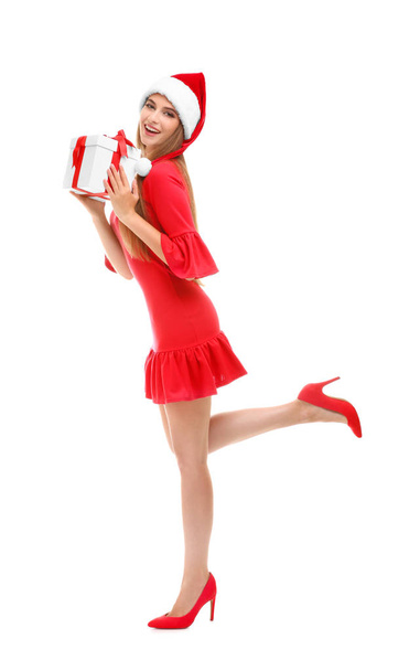 Beautiful young woman in Santa hat holding giftbox, on white background - Фото, изображение