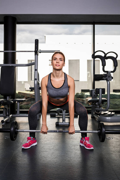 Woman doing exercises with barbell in the gym - Fotoğraf, Görsel