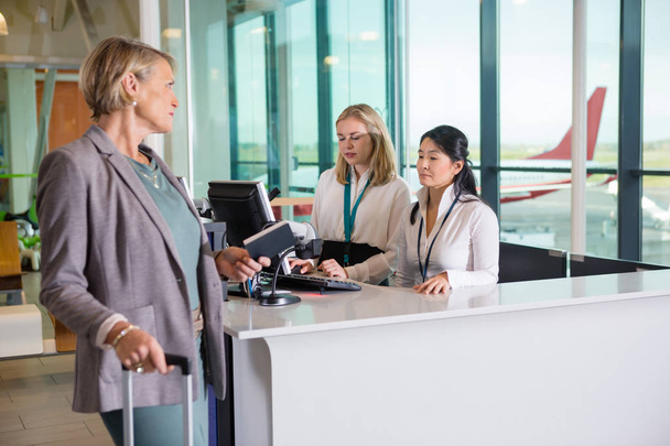 Passenger Looking At Receptionists Working At Airport Counter - Foto, Imagem