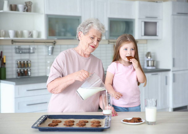 Little girl and grandmother on kitchen - 写真・画像