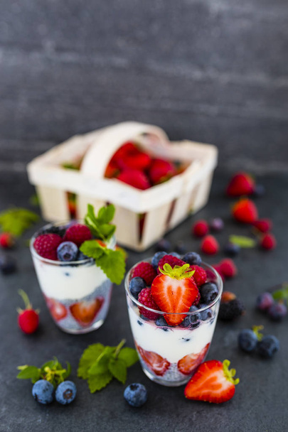 Йогурт со свежими ягодами и семенами чиа на тёмном фоне
. - Фото, изображение