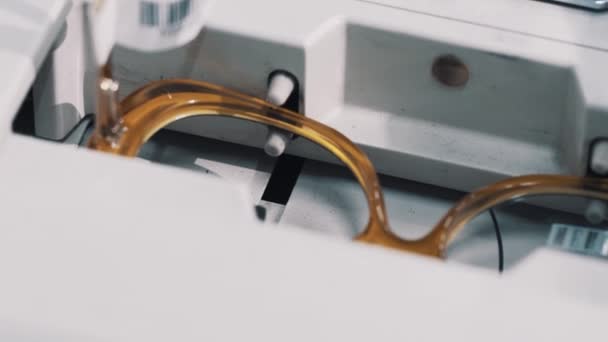 Brązowe szkła plastikowe ramki w optyk maszyna pomiarowa - Materiał filmowy, wideo