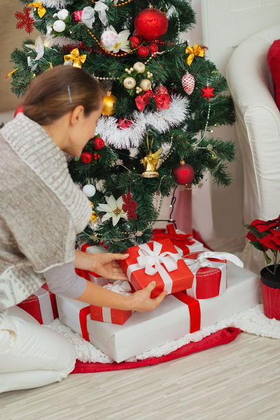 Woman putting Christmas present box under Christmas tree. Rear v - Fotoğraf, Görsel