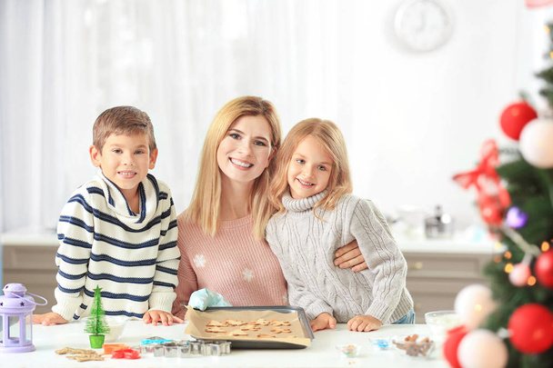 Young woman preparing Christmas cookies with little children in kitchen - Foto, imagen