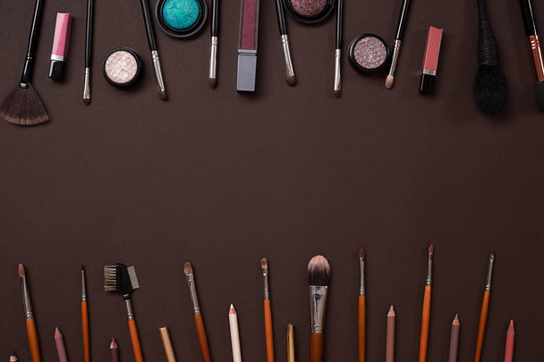 Various cosmetics and brushes on brown background - Фото, зображення