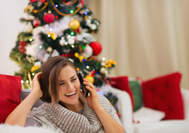 Happy woman near Christmas tree speaking mobile - Foto, Imagen