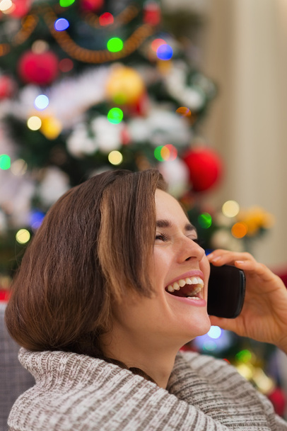 Portrait of smiling woman speaking mobile near Christmas tree - Foto, Bild