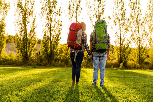 young couple with backpacks on meadow - Foto, afbeelding