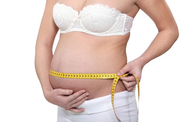 Pregnant woman measuring her abdomen - Valokuva, kuva