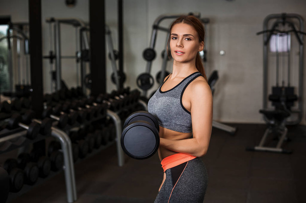 Spor salonunda dumbbells ile egzersizleri yapıyor kadın - Fotoğraf, Görsel