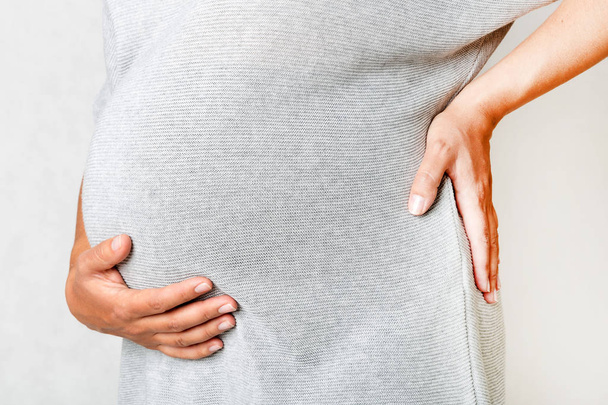 беременная женщина держит руки на животе и спине
 - Фото, изображение