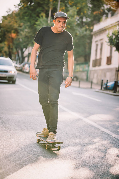 Pro skateboard rider in front of car on city road - Fotó, kép