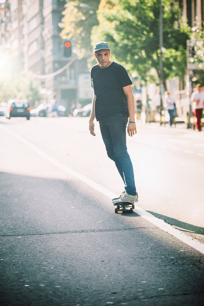 Pro skateboard rider in front of car on city road - 写真・画像