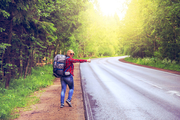 Chica solitaria haciendo autostop en la carretera con una mochila
. - Foto, Imagen