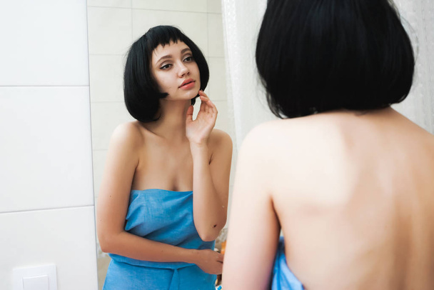 lovely girl with short black hair after a shower looks in the mirror - Photo, image