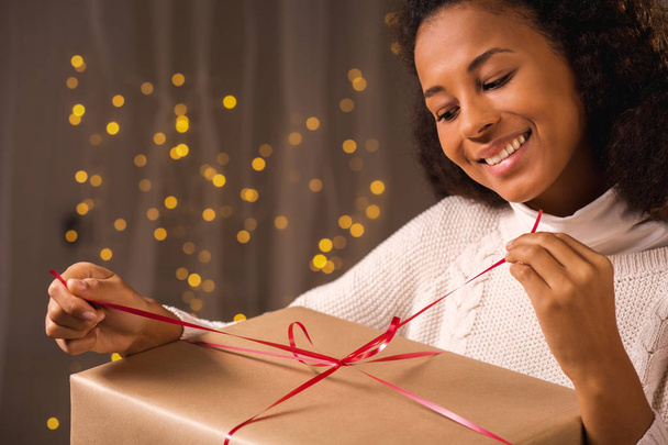 Smiling woman unwraping a present - Φωτογραφία, εικόνα