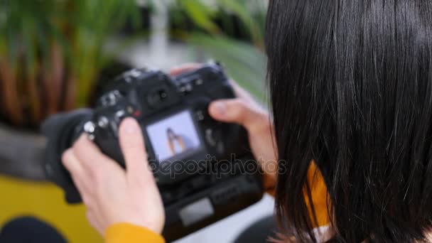 女性のカメラマンがデジタル一眼レフ カメラからの画像を見る - 映像、動画
