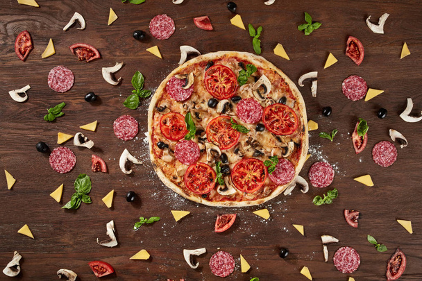 Pizza with tomatoes, mozzarella cheese, black olives and basil. Delicious italian pizza on wooden pizza board. - Photo, Image
