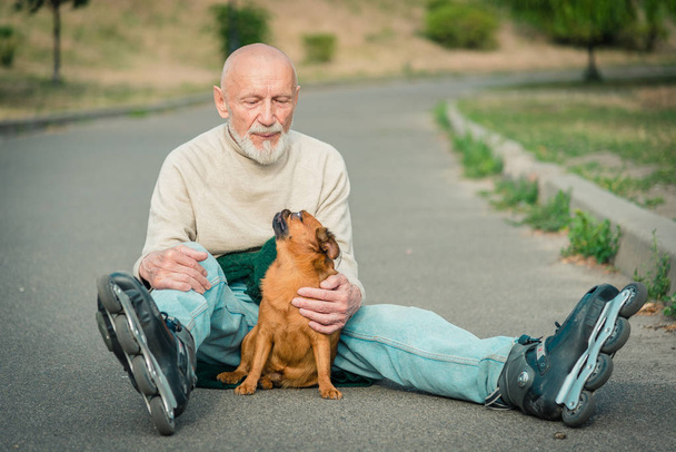 Grandpa rolls on roller with a dog of the Griffon breed - Φωτογραφία, εικόνα