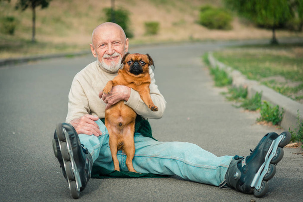 Grandpa rolls on roller with a dog of the Griffon breed - Photo, Image