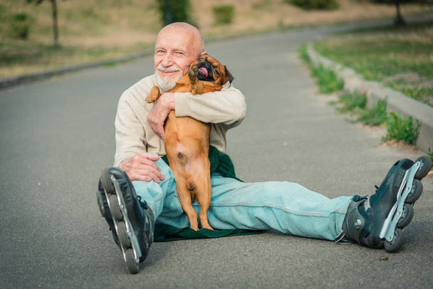 Grandpa rolls on roller with a dog of the Griffon breed - Zdjęcie, obraz