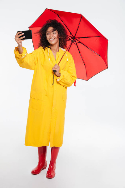 Full length image of happy african woman in raincoat - Foto, Imagen