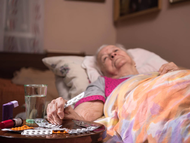  Sick old woman lying in bed at home - Fotó, kép