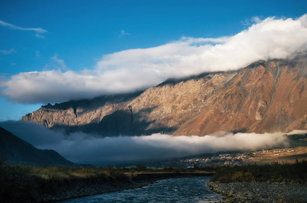 Different layers of clouds over Stepantsminda village and mountain, Georgia. - 写真・画像