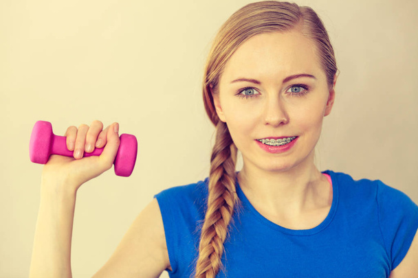 Teenage woman working out at home with dumbbell - Фото, изображение