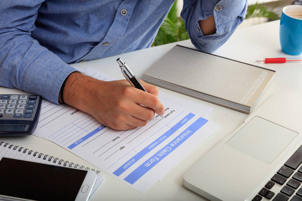 Homme préparant un formulaire de réclamation d'assurance
 - Photo, image