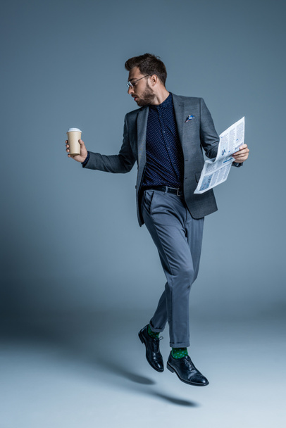 Businessman walking with coffee and newspaper - Fotoğraf, Görsel