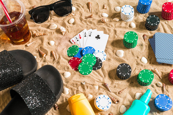Glücksspiel im Urlaub - weißer Sand mit Muscheln, farbigen Pokerchips und Karten. Ansicht von oben - Foto, Bild