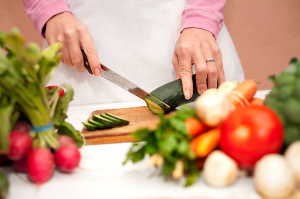 Woman cutting vegetables with a knife - 写真・画像