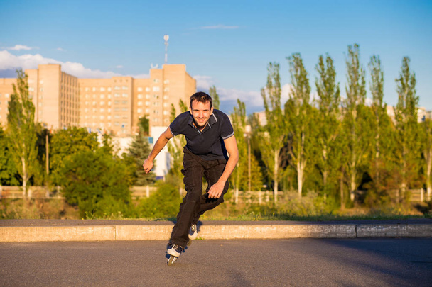 Happy young man rollerblading in city park at sunset - Foto, Imagen