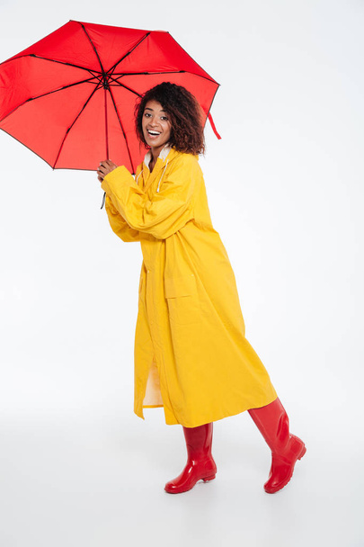 Full length image of Smiling african woman in raincoat - Fotó, kép