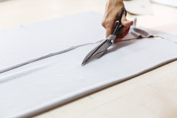 Mujer manos de costurera cortando un tejido gris con tijeras
 - Foto, imagen