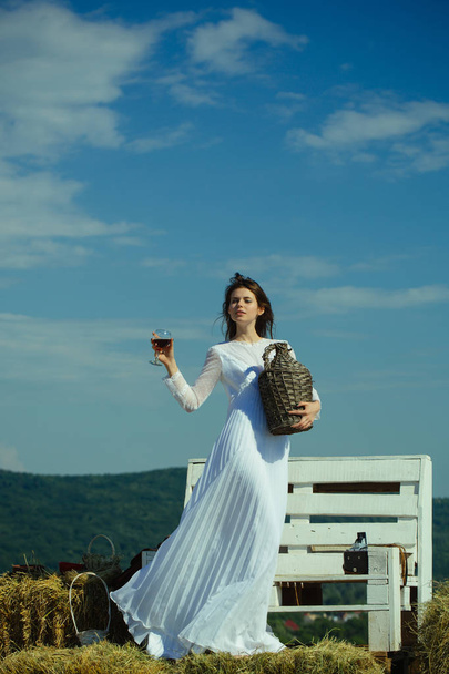 Woman with glass of red wine and wicker bottle - Zdjęcie, obraz