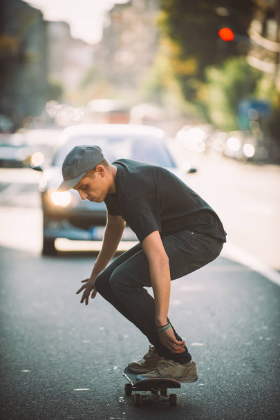 Pro skateboard rider in front of car on city street - Фото, изображение